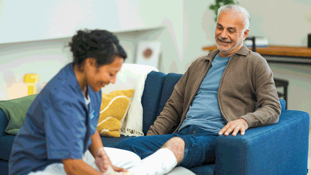 A photo of a nurse helping an elderly man with a leg ulcer.