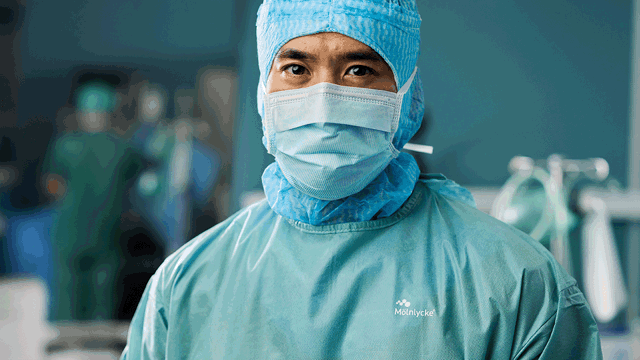 A person wearing a surgical gown and mask. Photo.