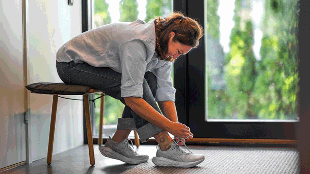 A woman tying her shoes. Photo.