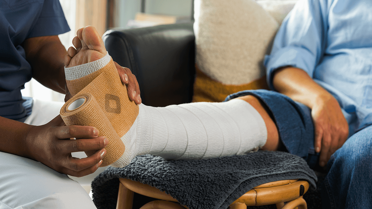 A nurse applying a compression bandage on a patient's leg.